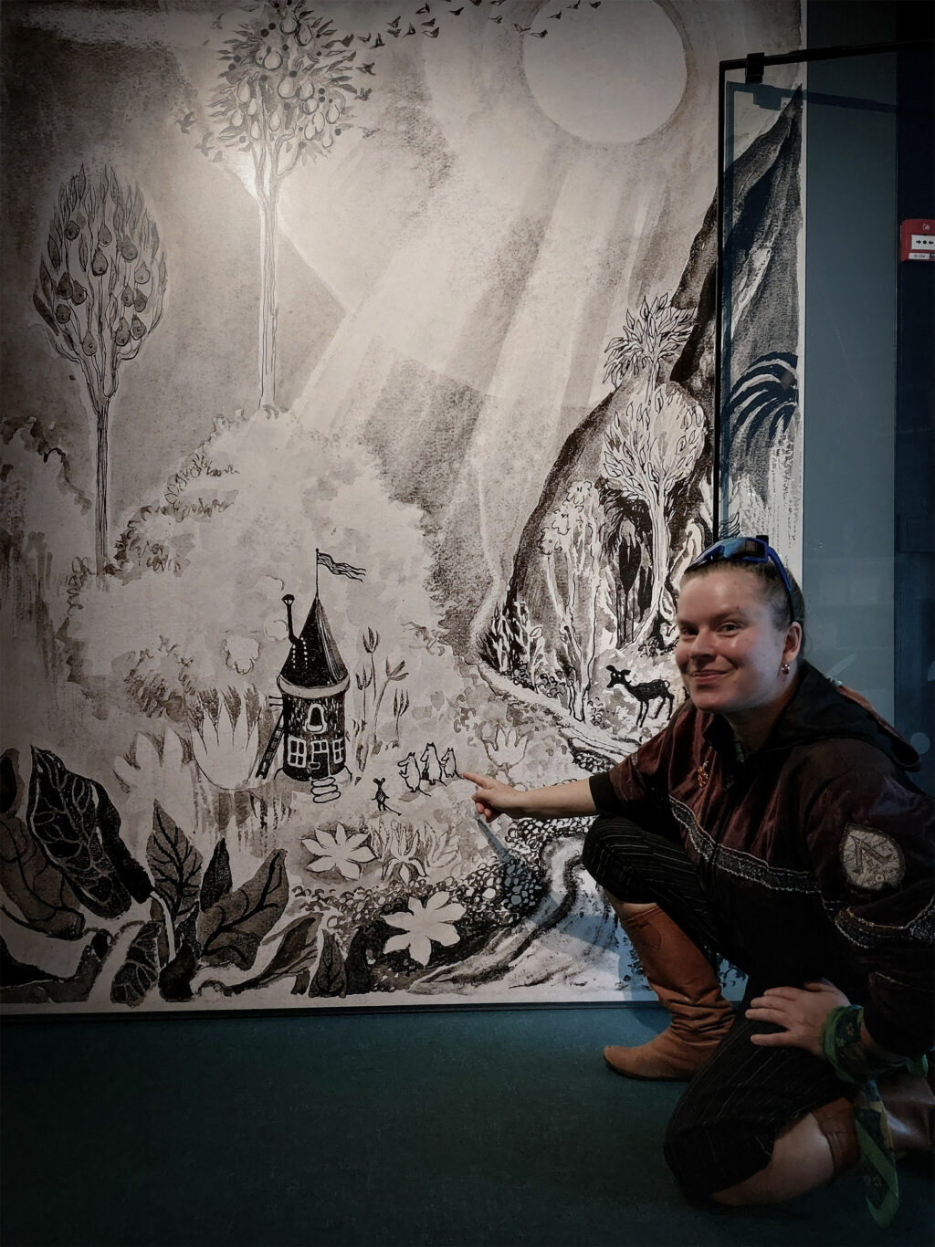 A lady is pointing a large Moomin image.